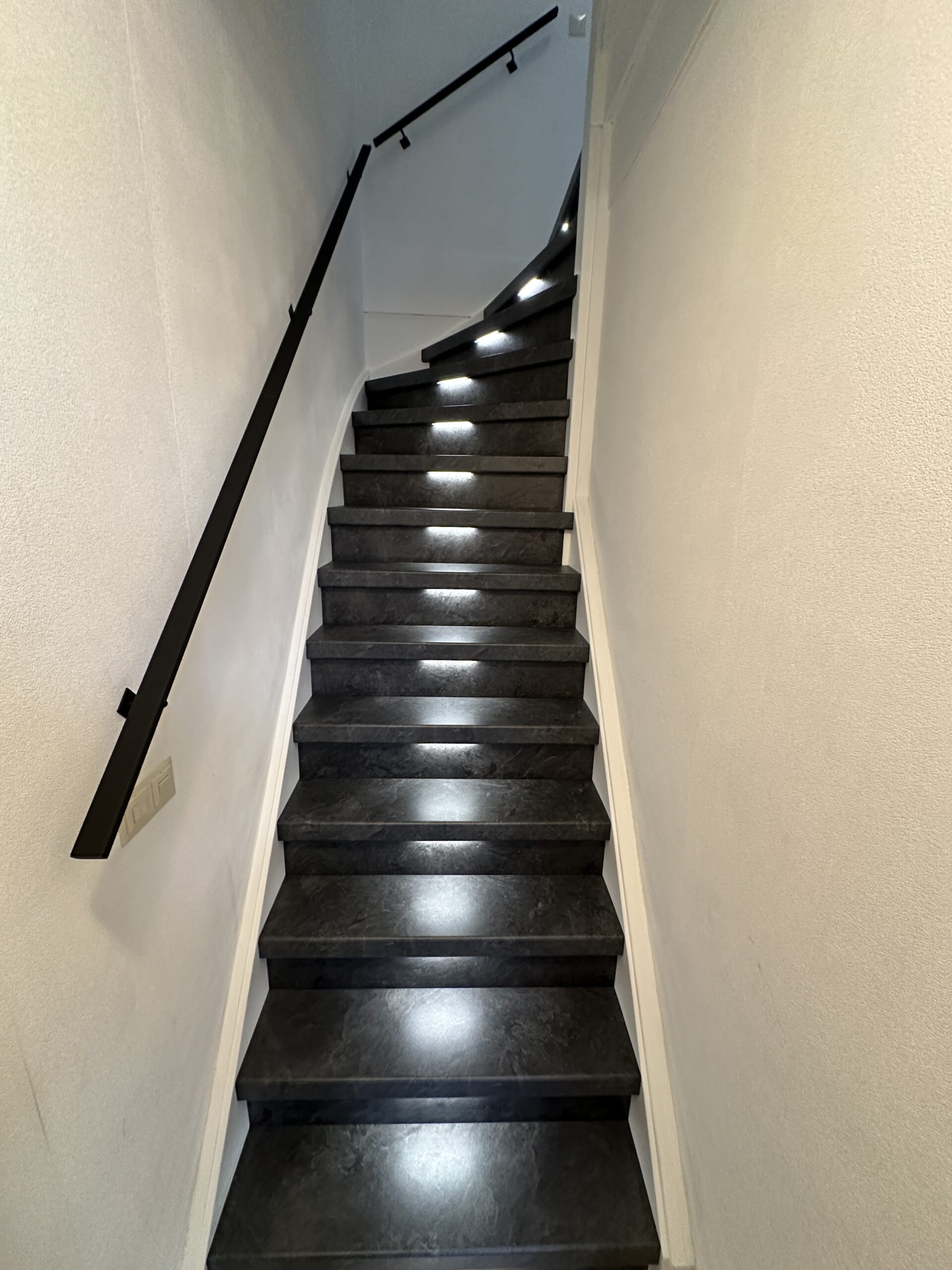 In Den Haag is deze trap gerenoveerd met het stijlvolle Mustang decor op de treden en stootborden. De uitlooptrede is afgewerkt met een zilverkleurig aluminium profiel. Dankzij draadloze bewegingssensoren wordt de LED-verlichting automatisch geactiveerd wanneer je de trap nadert. Bovendien kun je eenvoudig de gewenste kleurtemperatuur instellen via een handige app. Ook hebben we de trapleuningen mogen vervangen, de klant koos voor de zwart gepoedercoate trapleuningen plat van vorm (1,5 x 4 cm) met mooie bijpassende leuninghouders.