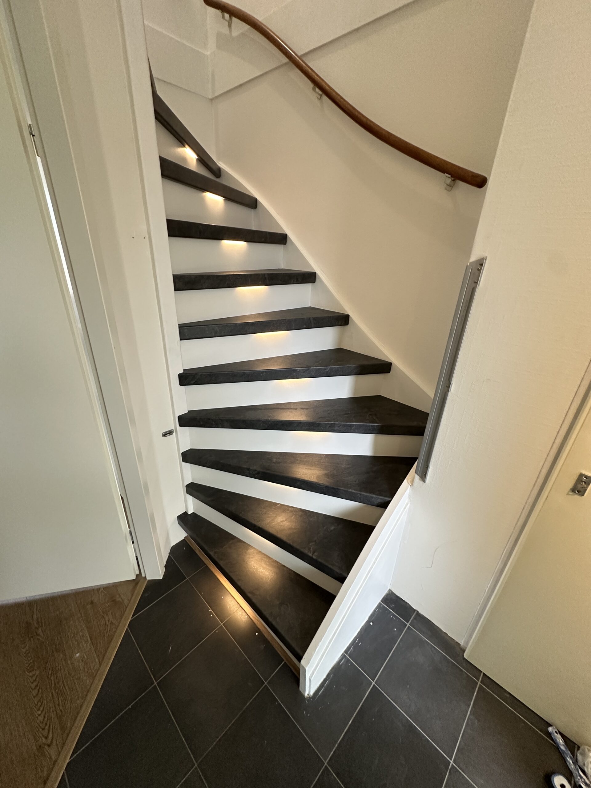 Voor deze klant in Leidschendam hebben we een dichte trap gerenoveerd incl. LED-verlichting. De klant koos voor het Mustang decor met witte stootborden. De laatste trede is mooi afgewerkt met een zwart aluminium profiel. De LED-verlichting gaat automatisch aan indien je je in de buurt van de trap bevindt, dit door draadloze bewegingssensoren. Ook kan de klant door middel van een app de kleurtemperatuur en kleursterkte bepalen.